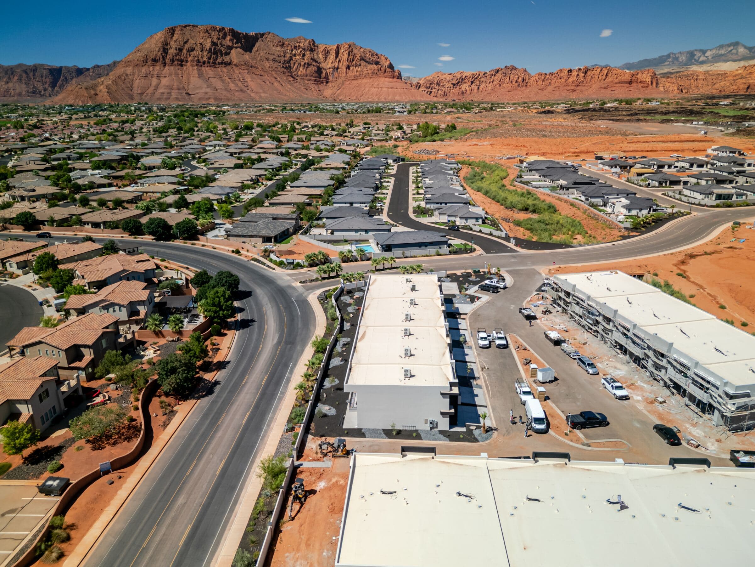 Aerial view of Solace Townhomes and the surrounding Santa Clara, Utah neighborhood with red rock cliffs behind